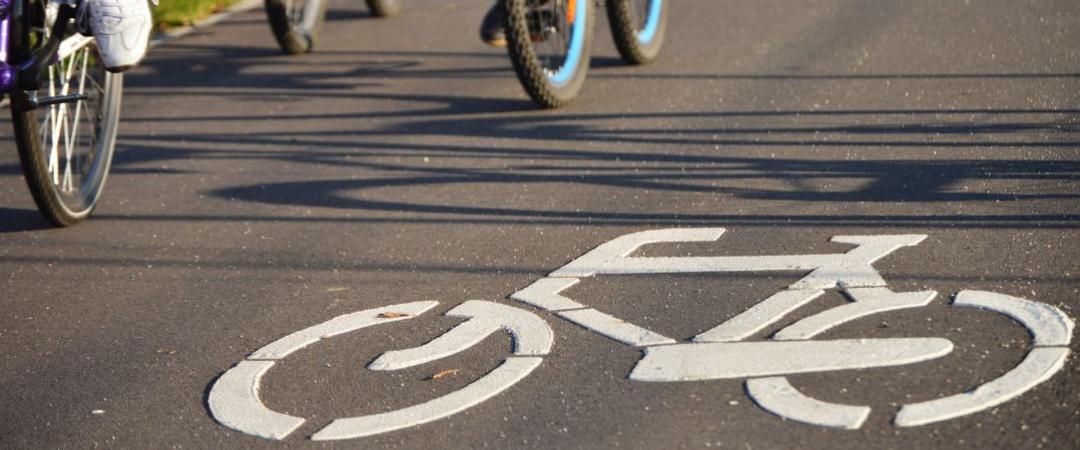 Bike symbol on road with people on bikes in the backround